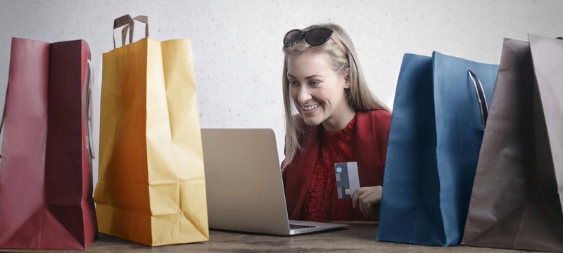 woman shopping on computer surrounded by shopping bags